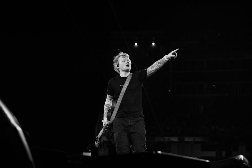 a black and white photo of ed sheeran performing on stage during a concert,