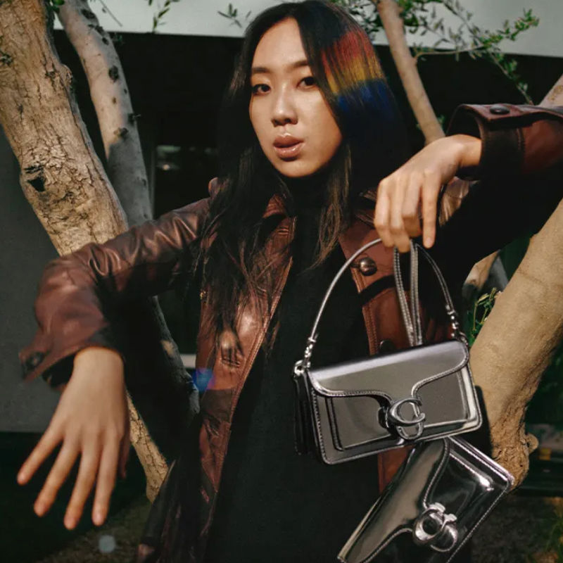 a photo of youngji lee holding a silver coach tabby 20 shine handbag