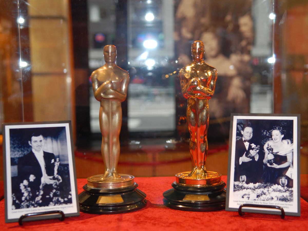 Academy Award Oscar statue with vintage movie reels on white Stock